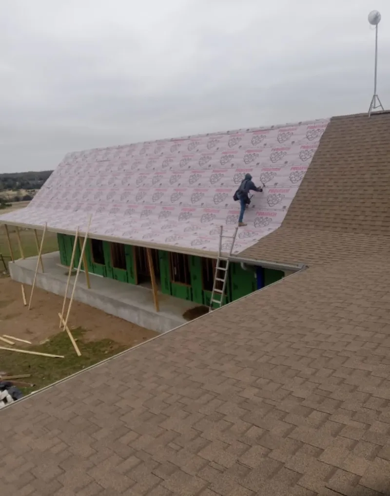 Worker preparing underlayment for a metal roof installation in Shorewood